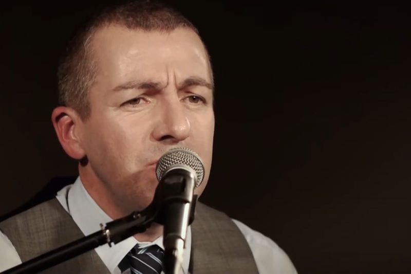 Darren Scott singing into a microphone during a live set